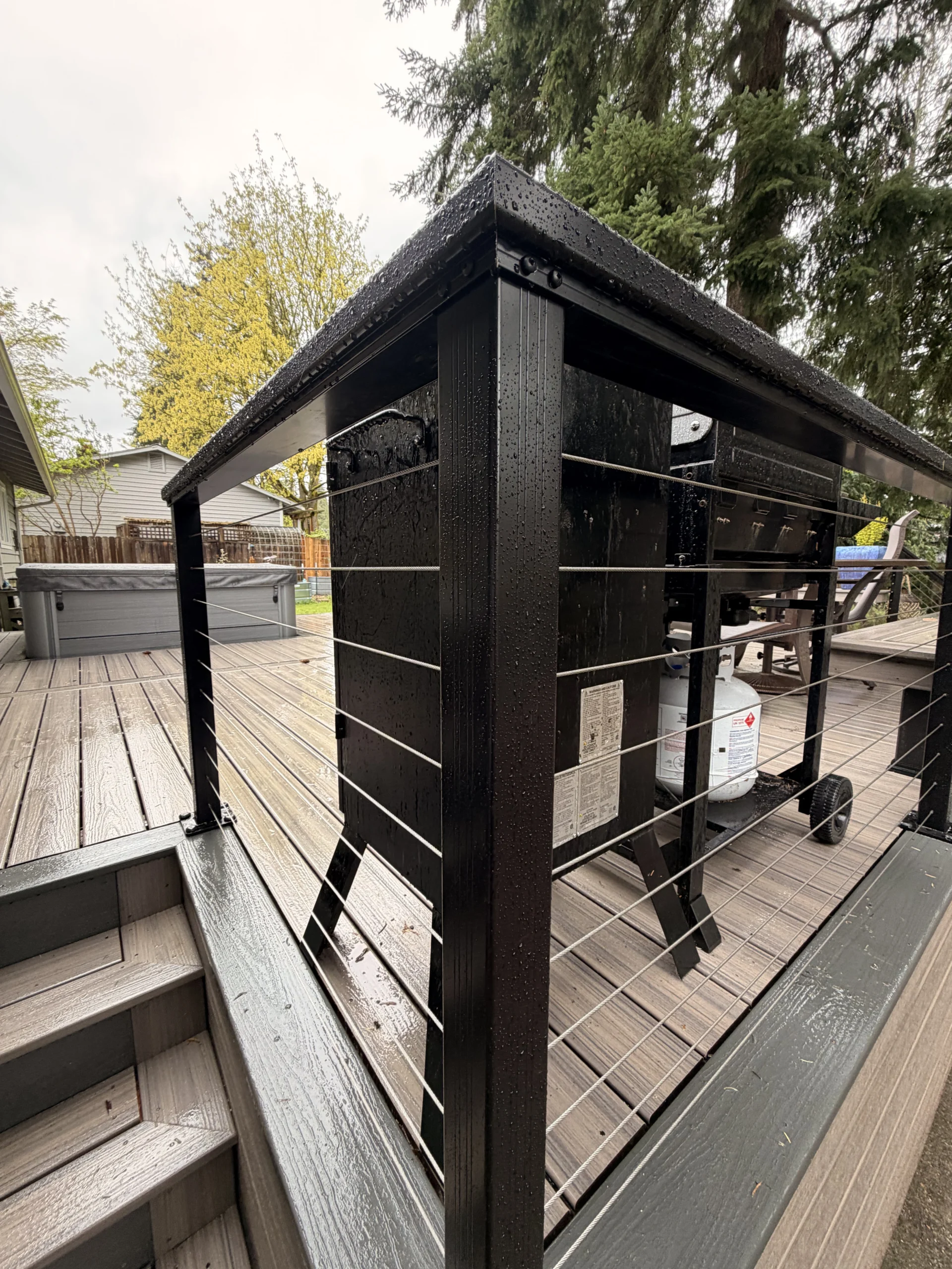 Wet black metal posts with sleek cable railings from a professional Composite Deck Installation in Seattle WA.