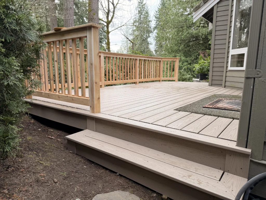 Olympic Decks A new composite deck installation in Mill Creek WA features durable taupe planks and a classic wooden railing.