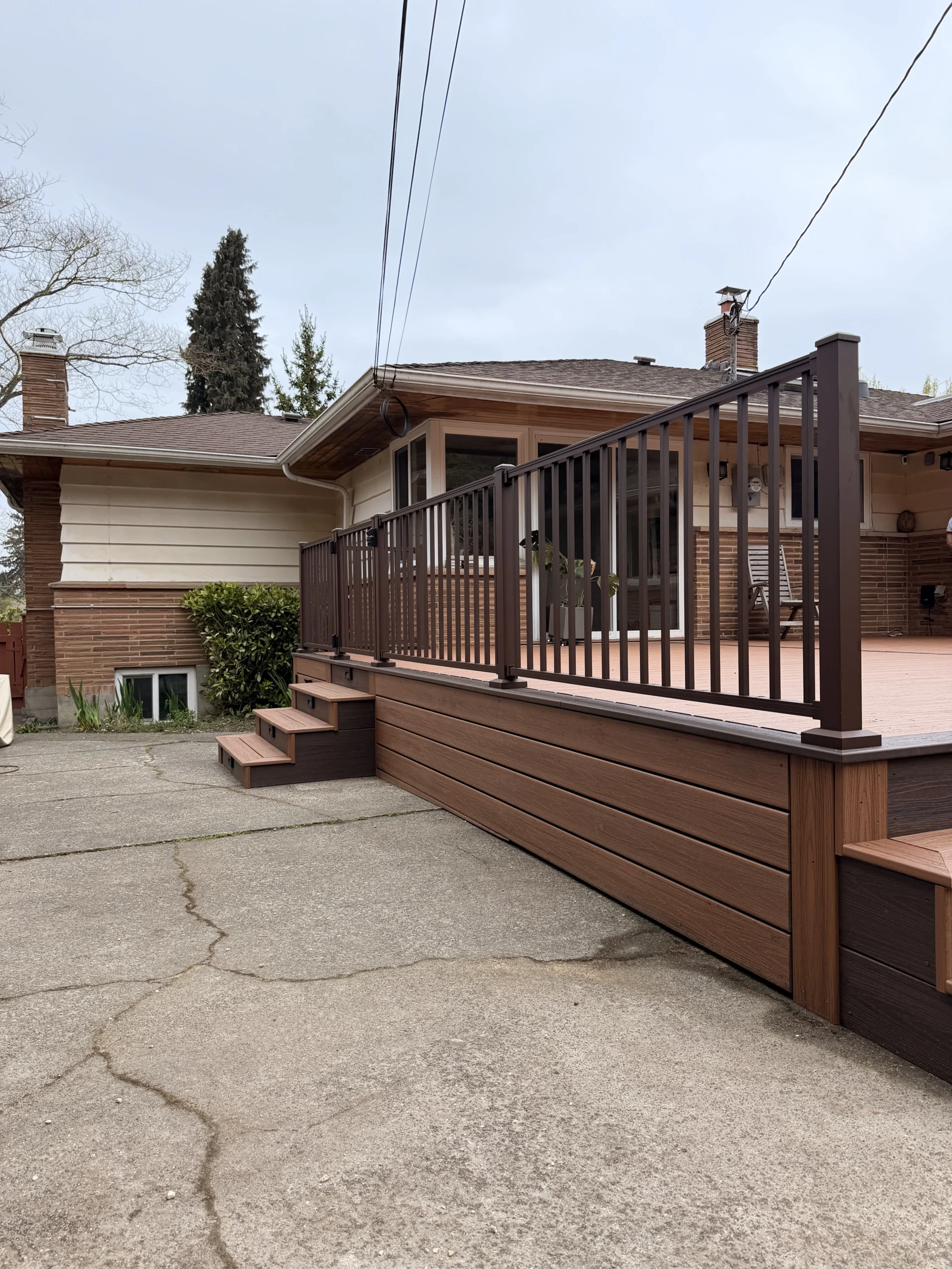 Beautiful Composite Deck Installation in Issaquah WA A newly completed composite deck installation in Issaquah WA featuring dark brown railings and steps.