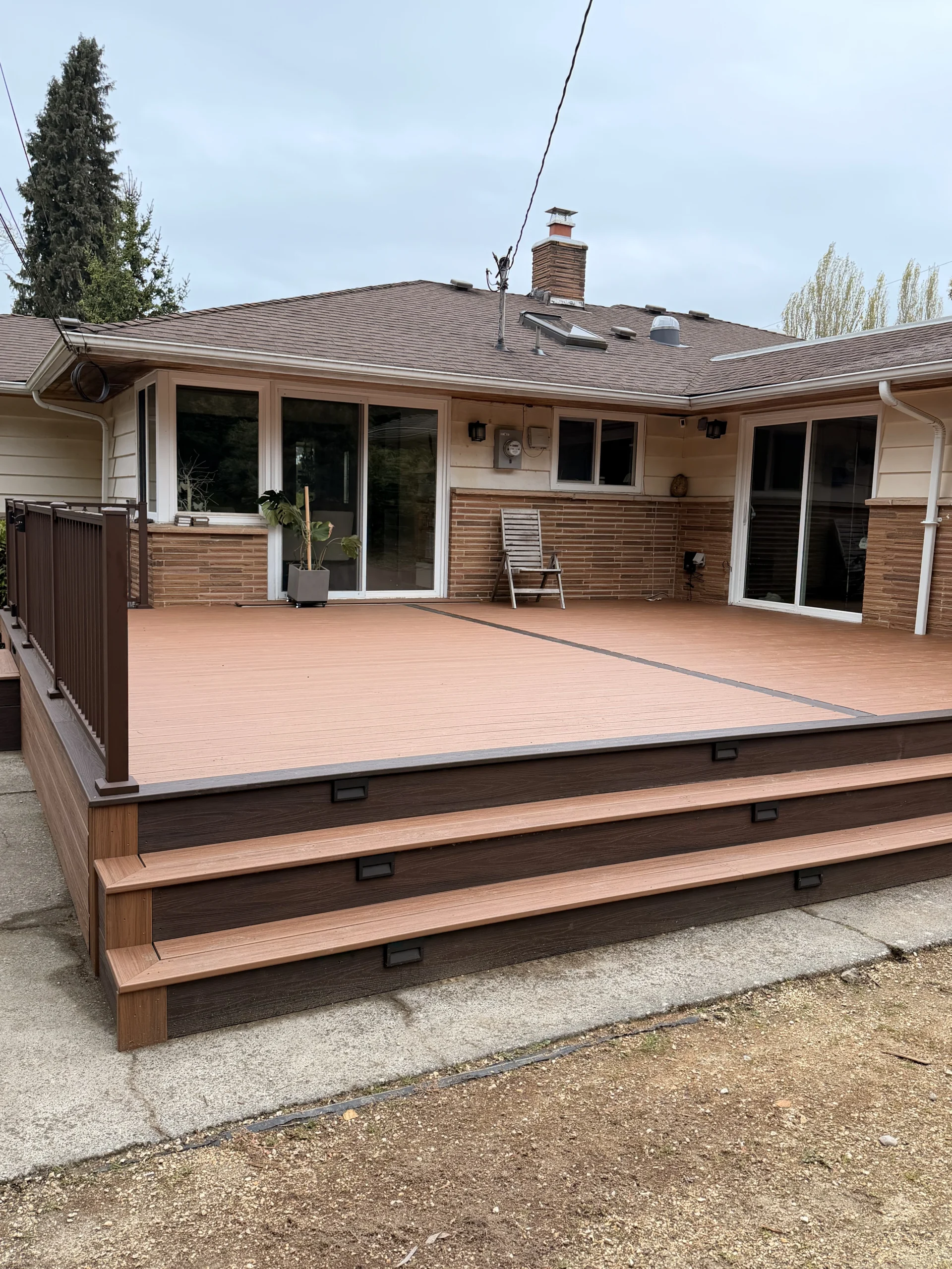 Wide-Angle Showcase of Composite Deck Installation in Issaquah WA A wide backyard shot of a completed two-tone composite deck installation in Issaquah WA with stairs