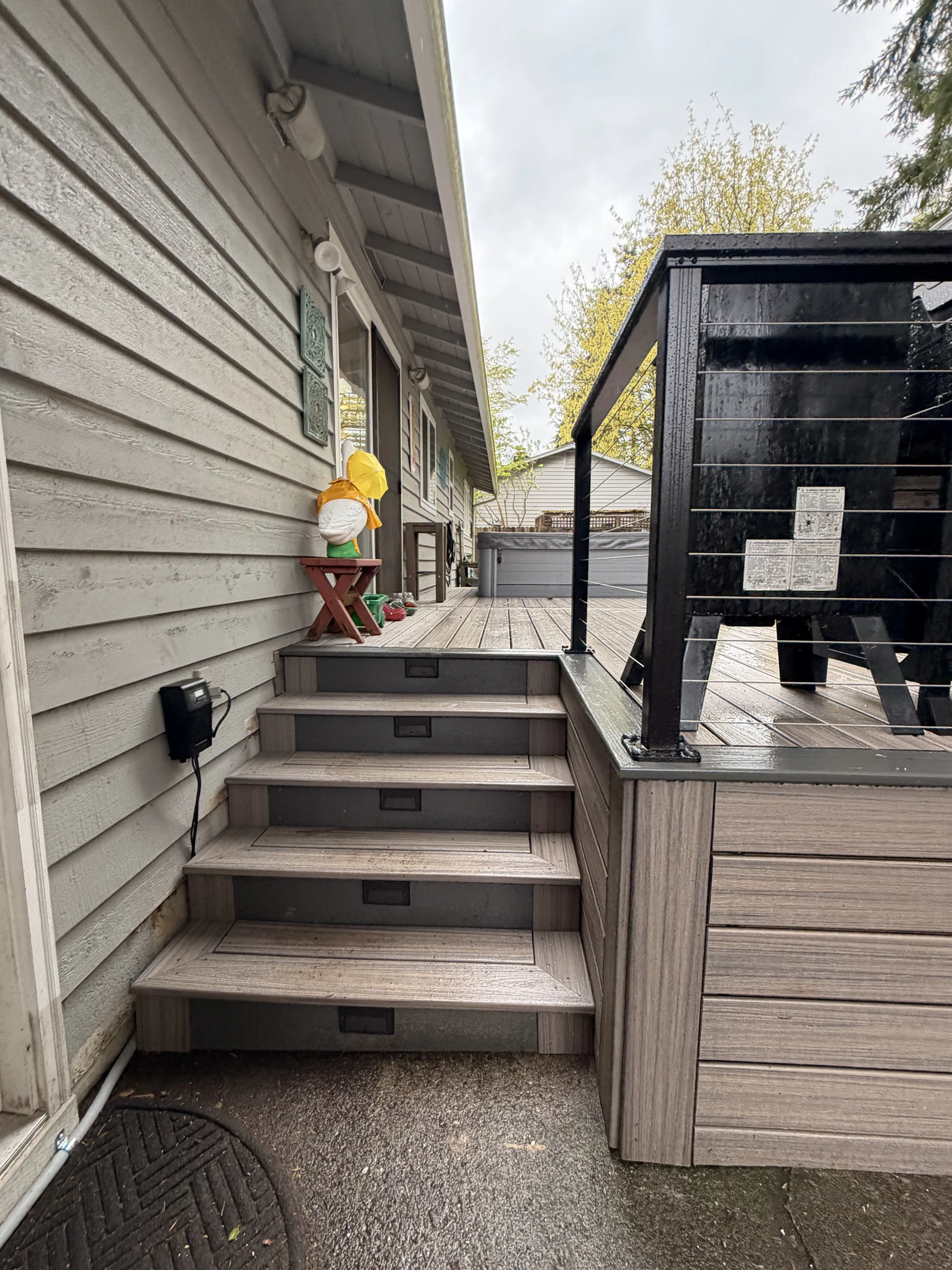 New grey steps with built-in lights from a professional Composite Deck Installation in Seattle WA next to a hot tub.