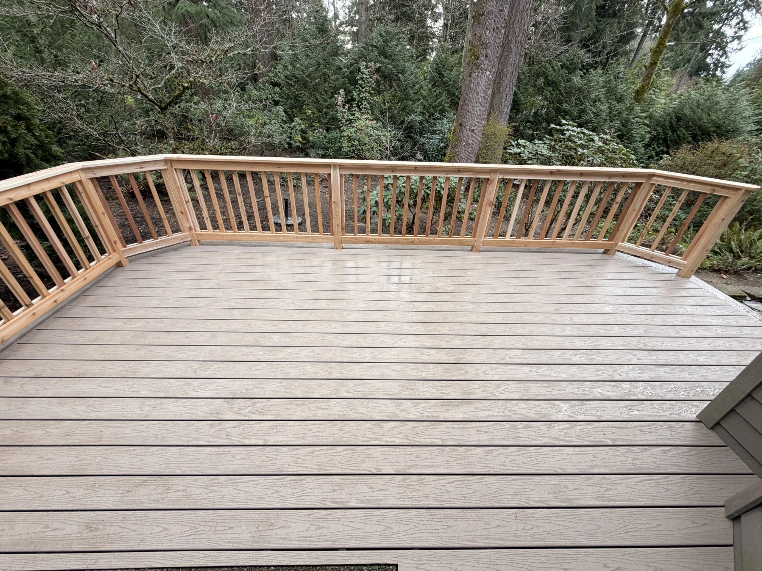 Spacious Backyard Composite Deck Installation in Mill Creek WA with Wood Railing Composite ground level deck with cedar railings and wide steps beside a Mill Creek home