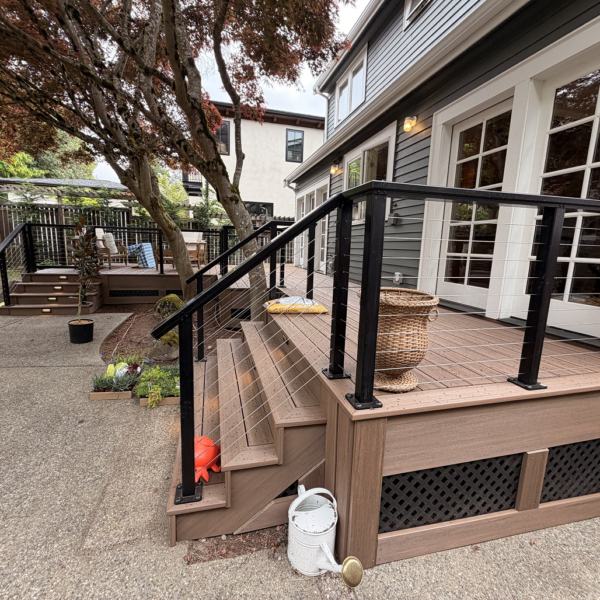 Side View Of Brown Composite Deck Steps With Black Cable Railing And Lattice Fascia.