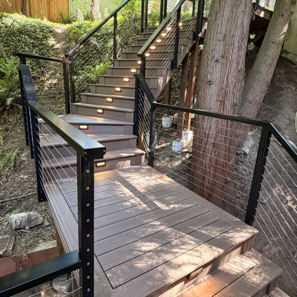 Perspective From A Deck Landing Showing A Turn In A Composite Stair System On A Wooded Hill.