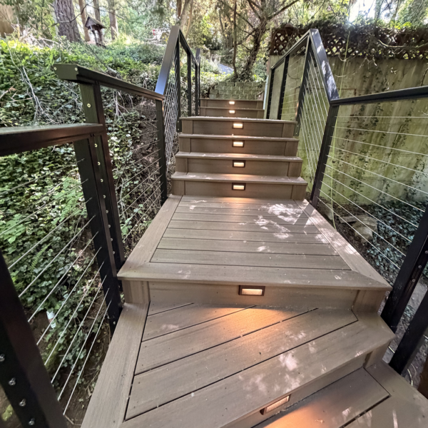 Looking Up A Curved Composite Staircase Built On A Wooded Incline With Led Step Lighting.