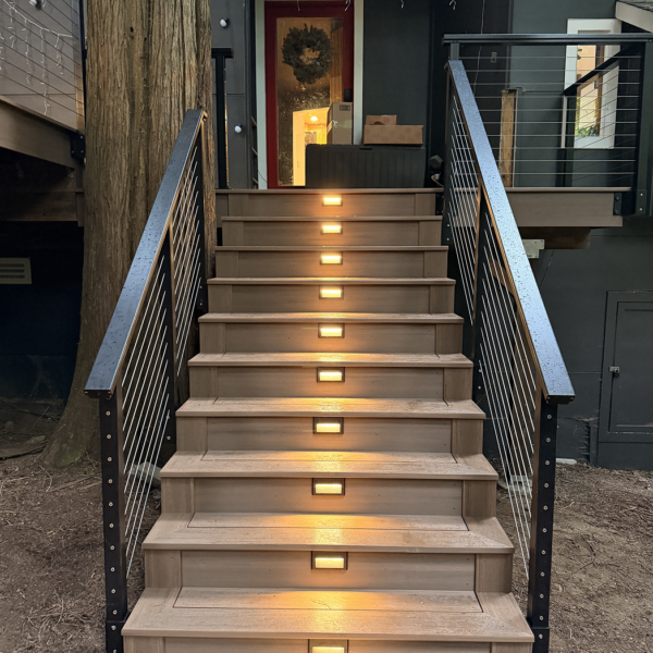 Straight-On View Of Illuminated Composite Steps Leading Up To A Home'S Entryway Door.