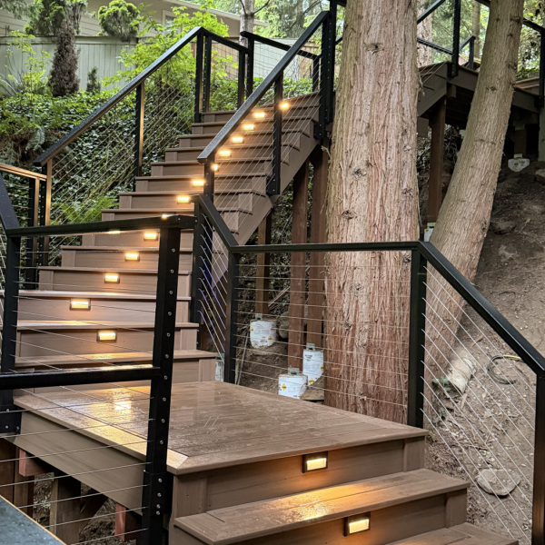 Custom Composite Staircase On A Wooded Hillside With Integrated Led Riser Lights And Black Cable Railings.