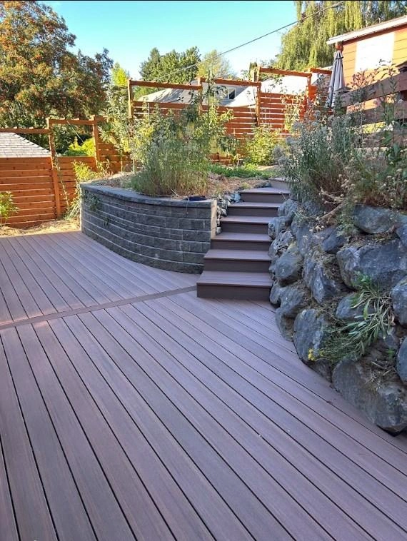 Dark Grey Tiered Composite Deck With Steps And Retaining Wall Following A Rotted Wood Deck Replacement.