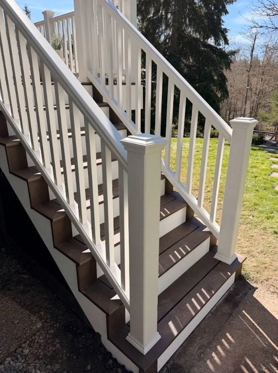 Outdoor composite stairs with white railings built during a Trex Transcend deck replacement.