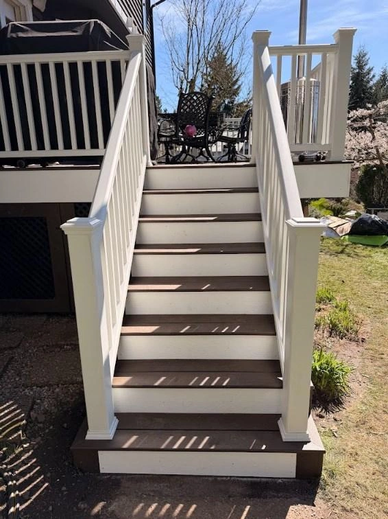 Composite outdoor stairs with white risers and railings built during a Trex Transcend deck replacement.