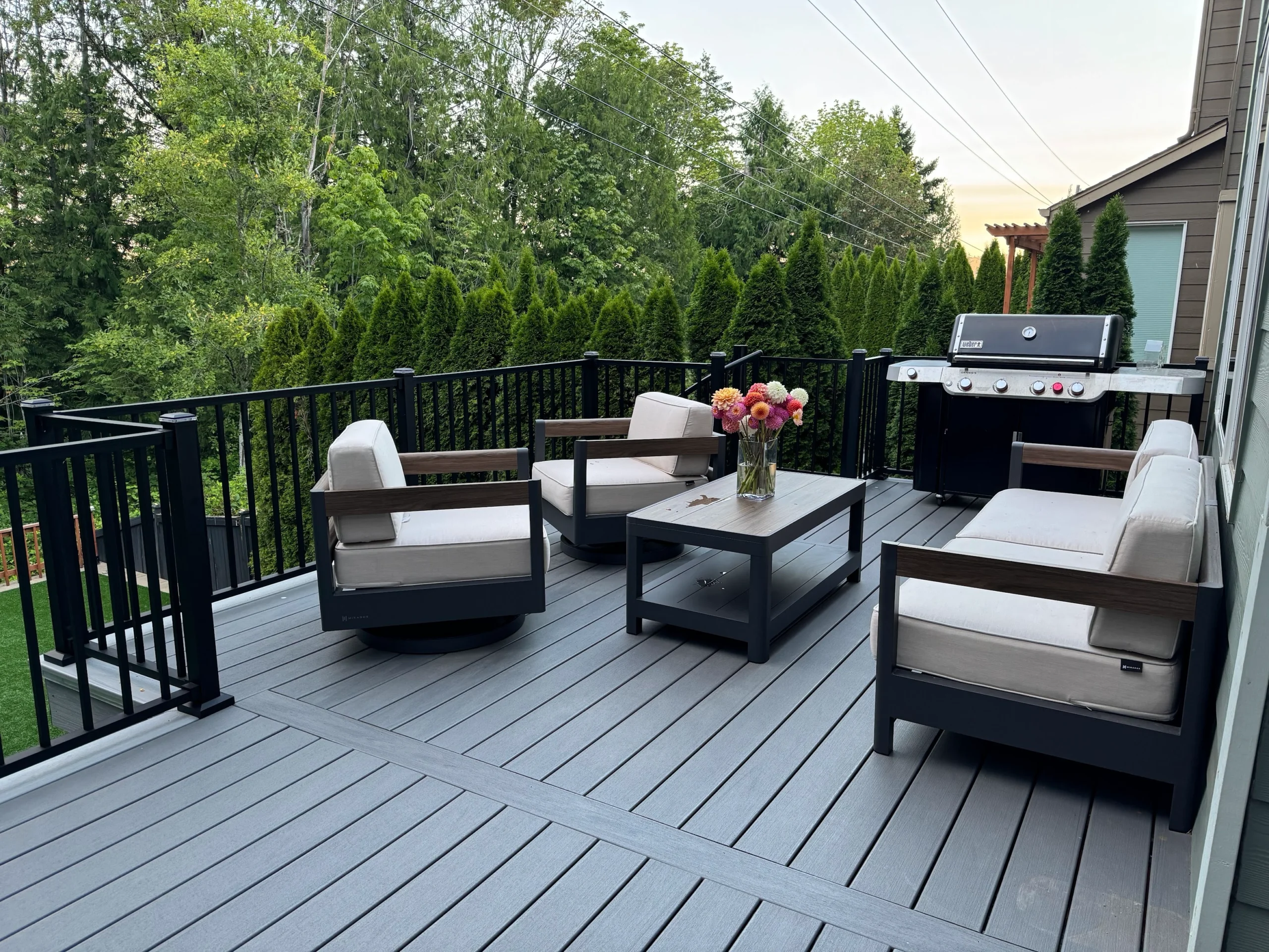 Comfortable outdoor seating area created with a fresh Trex deck replacement in Issaquah. Furnished Trex Lineage Deck With Black Aluminum Railing And Outdoor Seating