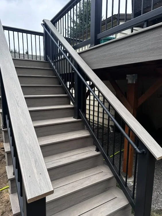 Complex railings and stairs for an AZEK Vintage deck replacement in Bellevue. Close-Up Of Grey Composite Stairs And Intricate Black Railings With An Attached Handrail, Part Of An Azek Vintage Deck Replacement In Bellevue.
