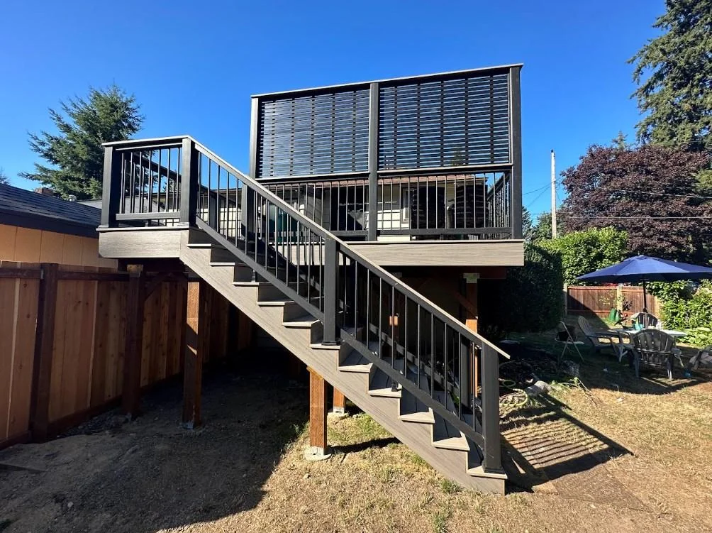 Completed elevated AZEK Vintage deck replacement in Bellevue with modern privacy screen. View From Below Of An Elevated Azek Vintage Deck Replacement In Bellevue, Featuring Black Railings And A Privacy Screen.