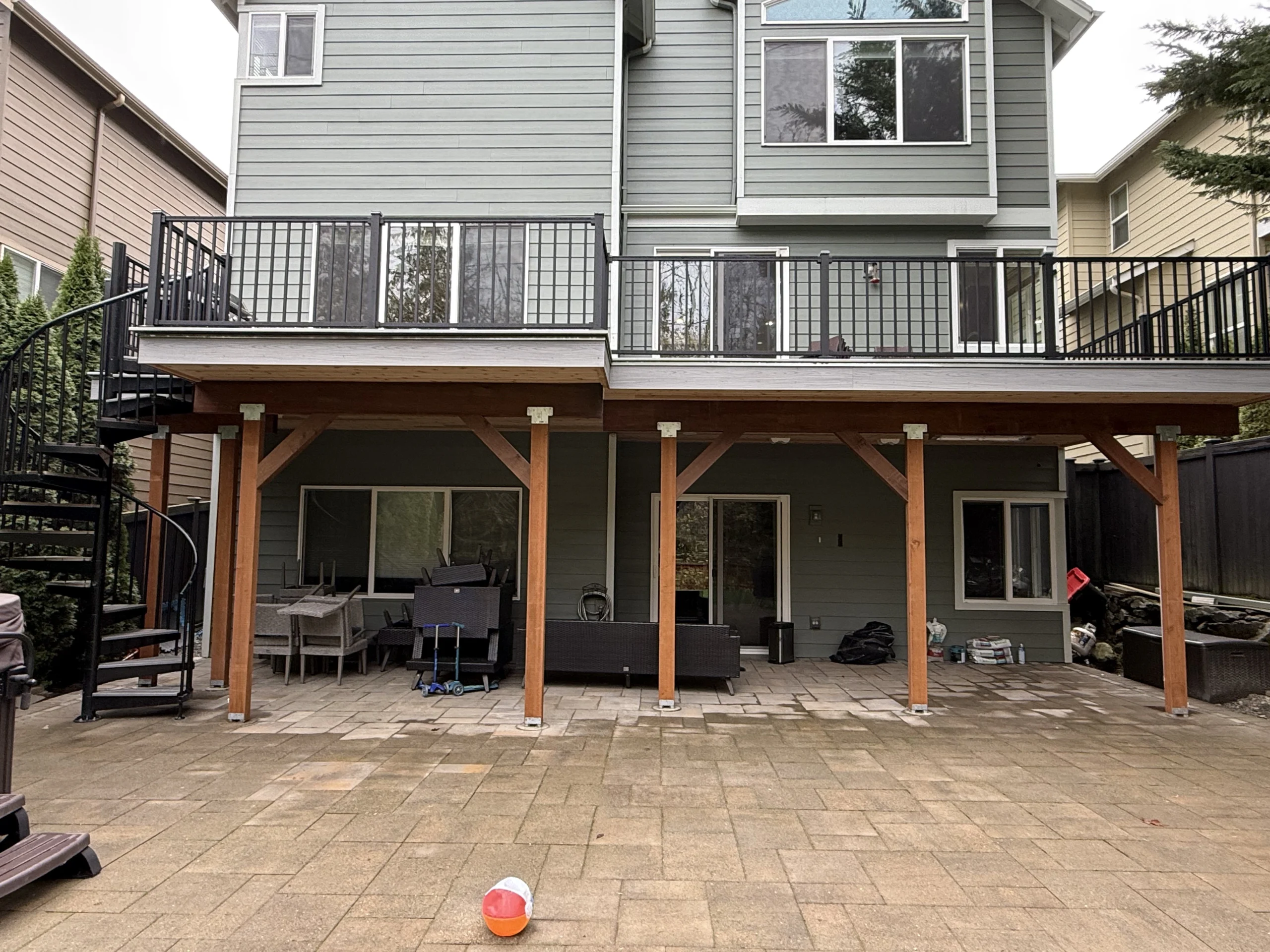 Elevated multi-level home structure featuring a professional Trex deck replacement in Issaquah. Elevated Trex Lineage Deck With Black Aluminum Railing And Spiral Staircase In Issaquah, Wa