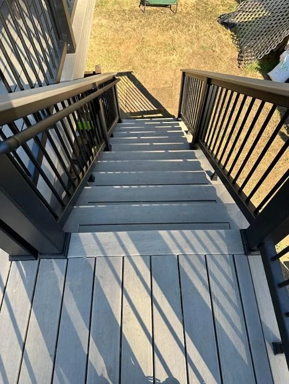 High quality AZEK Vintage deck replacement in Bellevue showing gray steps and black railings viewed from above. Top-Down View Of Gray Composite Stairs And Black Railings From An Azek Vintage Deck Replacement In Bellevue.