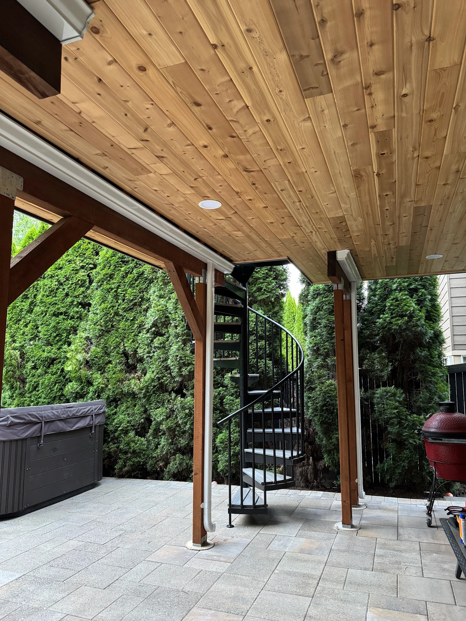 Black metal spiral staircase connecting levels in a Trex deck replacement in Issaquah. Spiral Staircase Beneath An Elevated Trex Lineage Deck In Issaquah, Wa