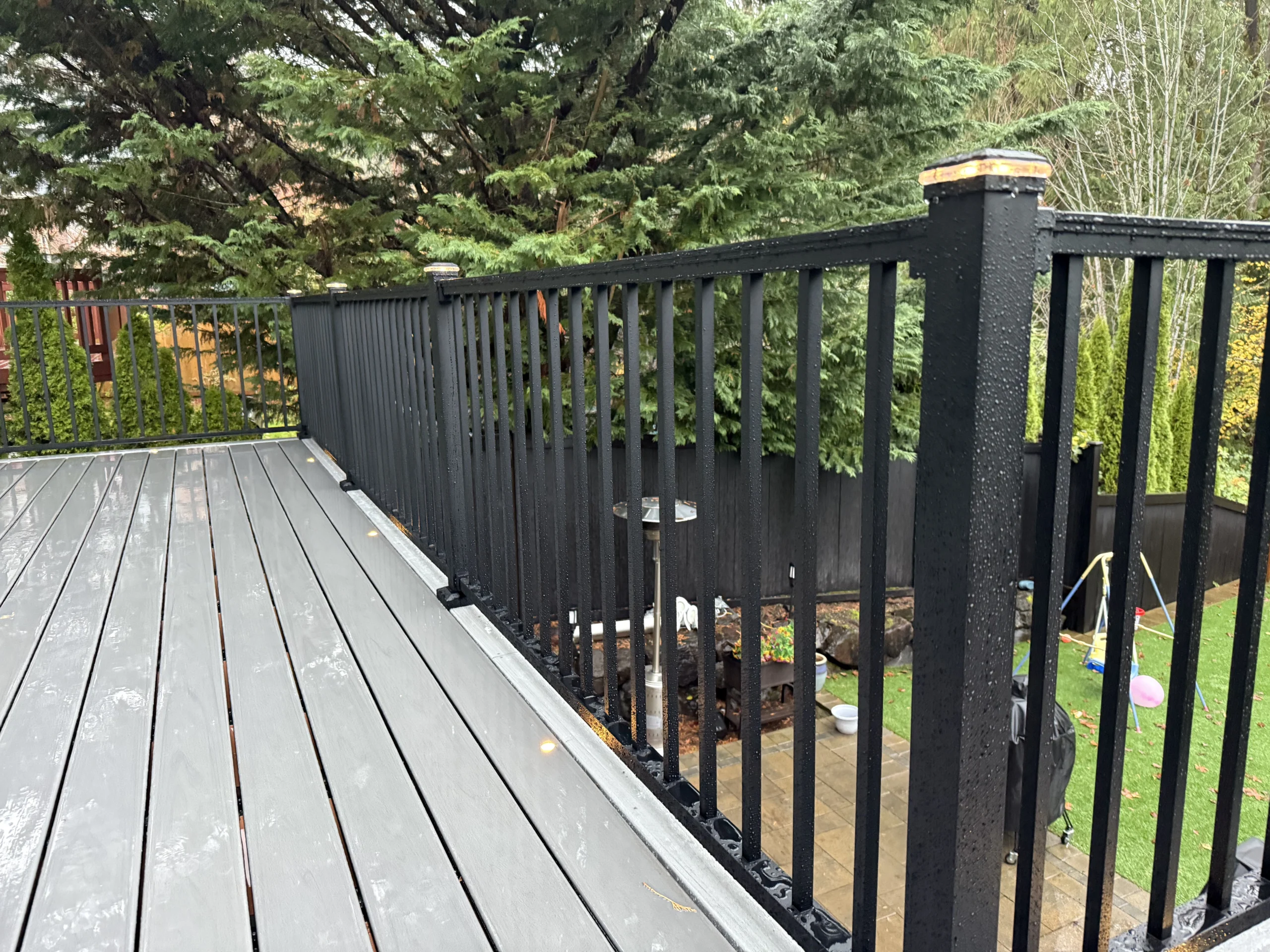 Modern composite outdoor living space highlighting a professional Trex deck replacement in Issaquah. Black Aluminum Railing Installed Along Trex Lineage Decking In Issaquah, Wa