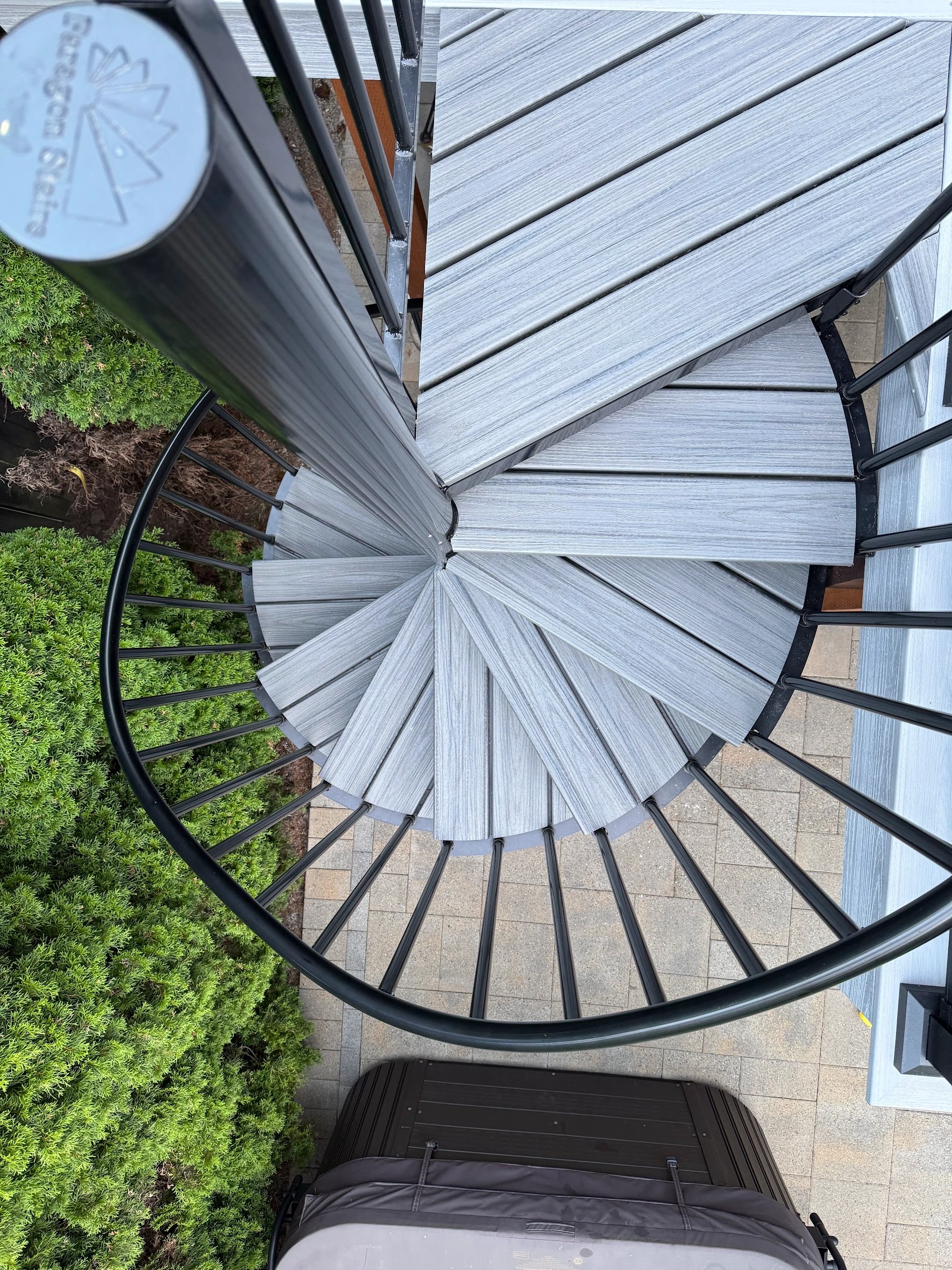 Top-down view of a spiral staircase with composite treads in a Trex deck replacement in Issaquah. Top View Of A Spiral Staircase With Trex Lineage Treads And Black Metal Railing