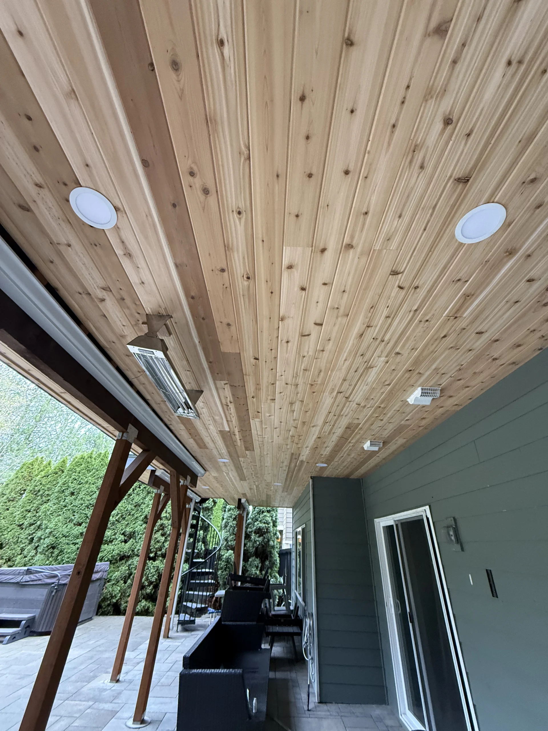 Natural wood soffit ceiling detail under a custom Trex deck replacement in Issaquah. Wood Ceiling With Recessed Lights Beneath An Elevated Trex Deck