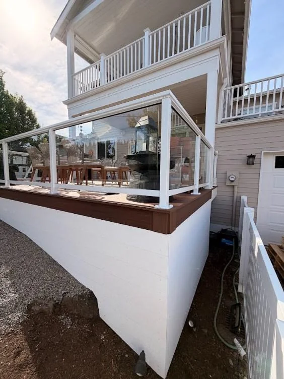 White-Walled Patio Structure Highlighting A Ground-Level Azek Deck Replacement In Edmonds With Glass Safety Railings.