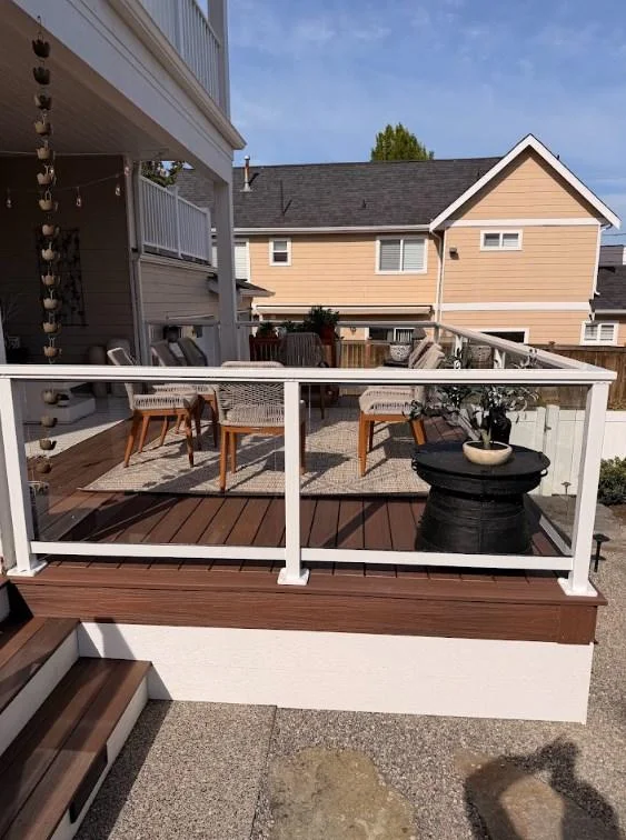 Outdoor Furniture Set Placed On A Ground-Level Azek Deck Replacement In Edmonds Behind Glass Railing Panels.