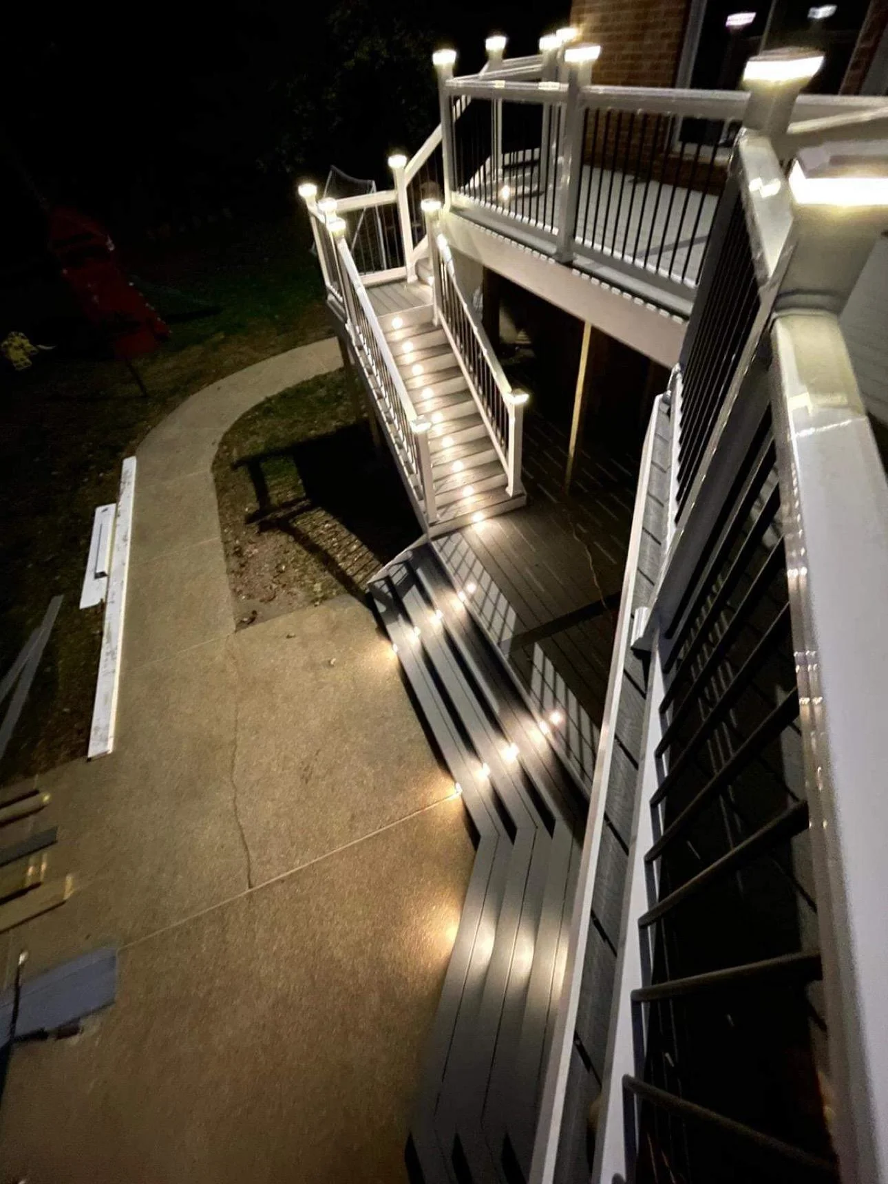 High-end deck replacement Everett WA staircase design View From The Upper Deck Of Lighted Stairs, A Landing, And Wide Lower Steps Leading To The Patio